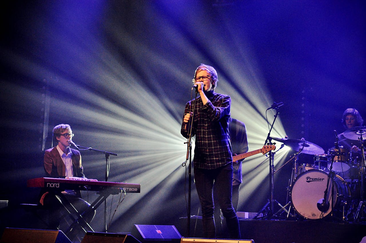 Energetic live music performance featuring a band on stage with dramatic lighting effects.